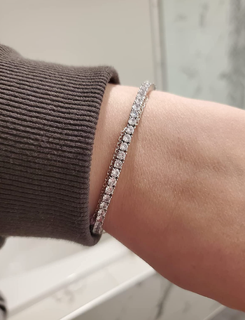 A reviewer showcasing a silver-plated faux diamond tennis bracelet, adding a touch of glamour to their look.