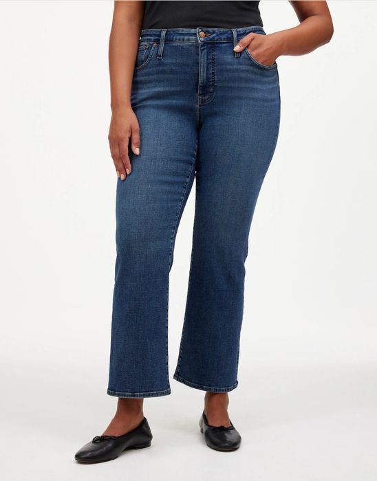 Person standing in straight-leg jeans and flats, casually posed against a simple backdrop.