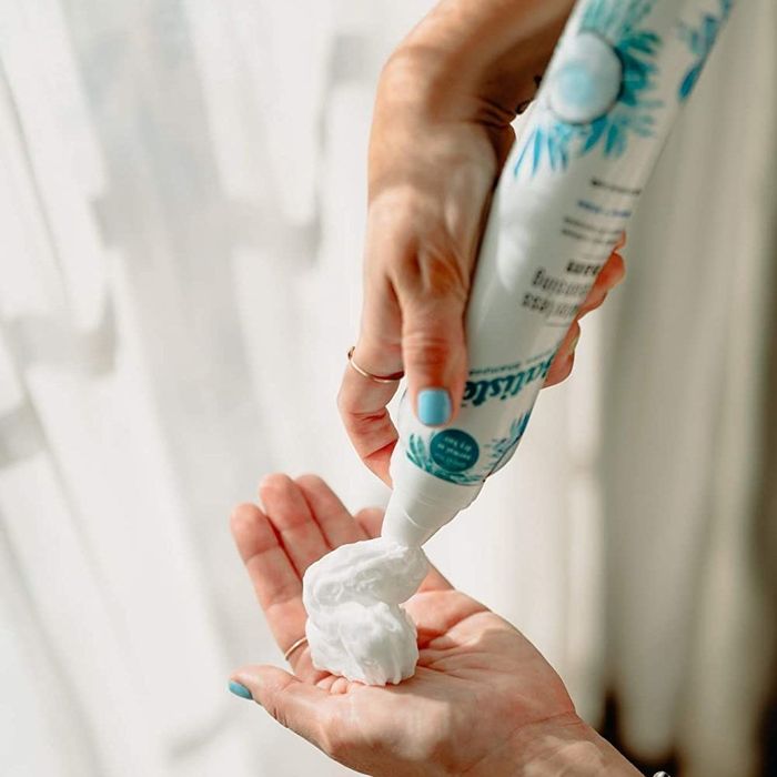 Model spraying dry shampoo foam into their palm