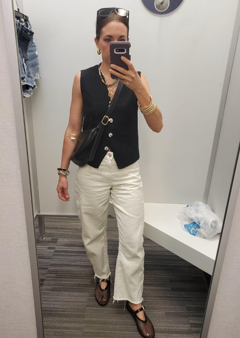 A reviewer modeling a black vest, showcasing its sleek and versatile design.