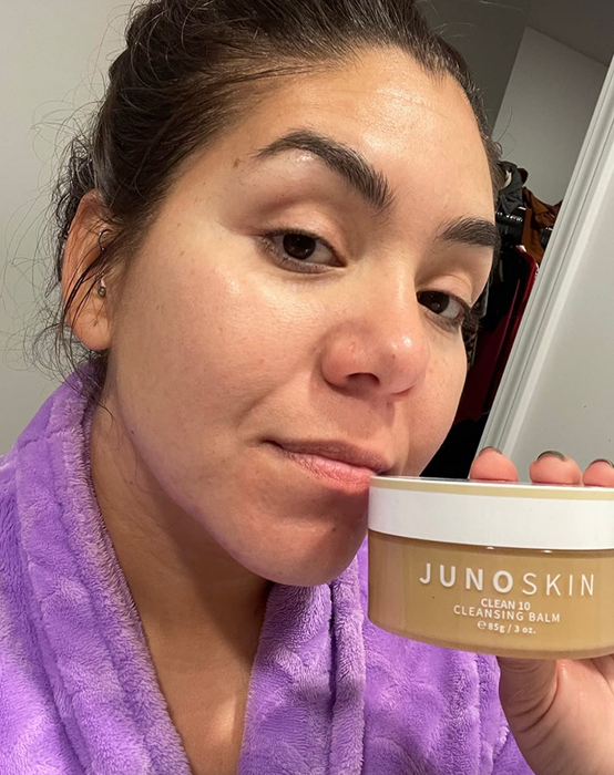 A reviewer holding a jar of the cleansing balm in hand.