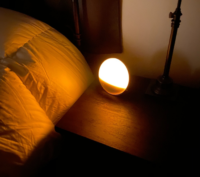 The alarm clock glowing with a soft, warm yellow light, ready to gently wake you up.