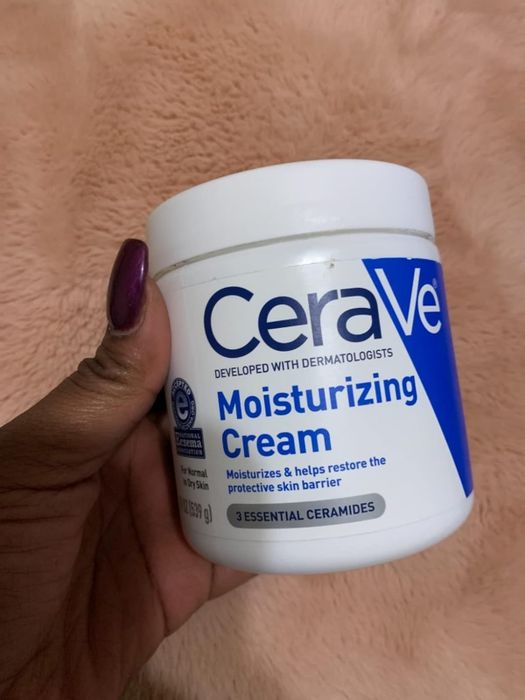 Reviewer holding the moisturizing cream bottle