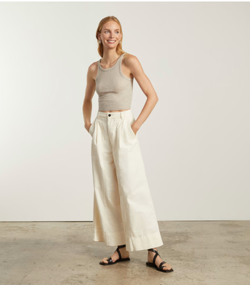 model wearing white wide-leg pants paired with a gray tank top and black sandals