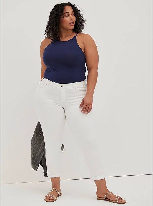 model styled in white cuffed jeans, a navy tank top, and sandals