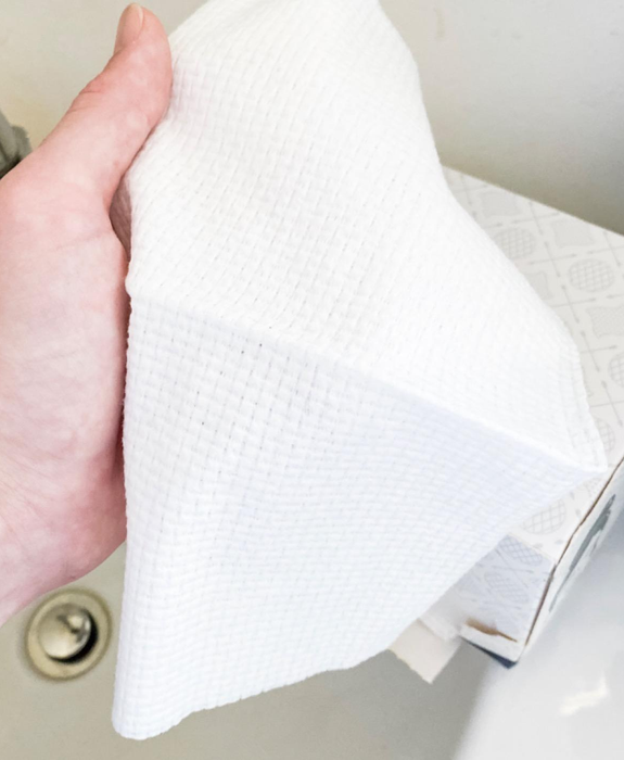 The reviewer holds one of the biobased disposable face towels in their hand.