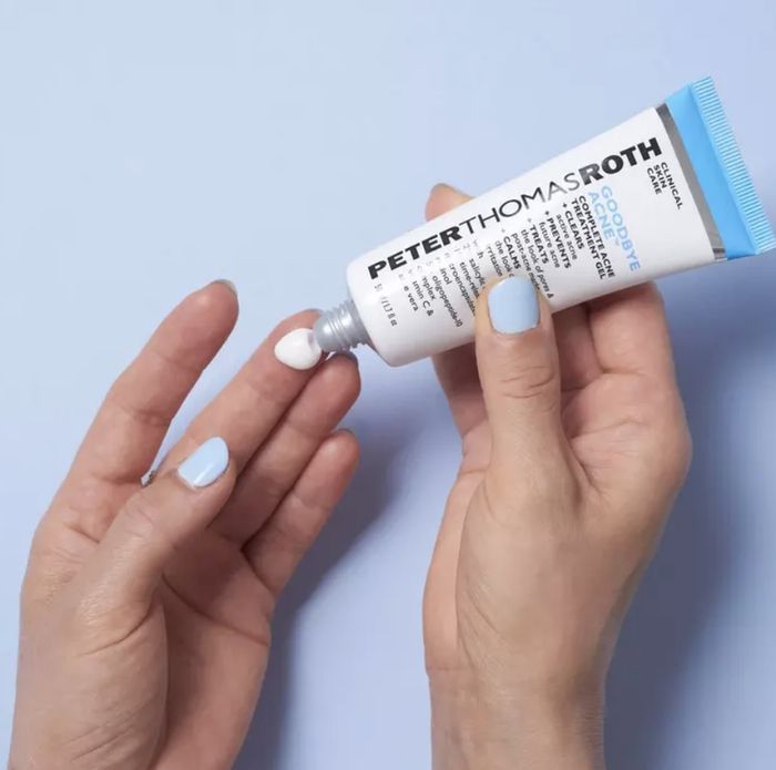 A hand gently squeezing lotion from a tube onto a fingertip.