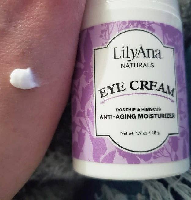 the tube of eye cream placed next to a hand with a small amount of the cream applied