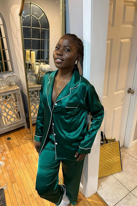 A reviewer relaxing in a green satin pajama set.