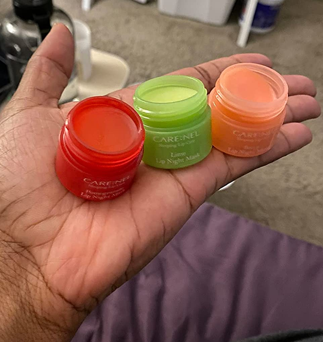 A hand holding all three tubs of the lip sleeping masks.