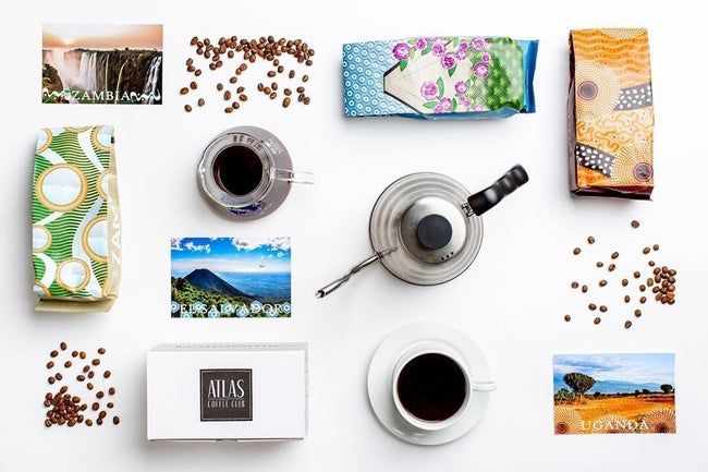 An aerial view of the subscription box, coffee bags, and cups of freshly brewed coffee spread across a table