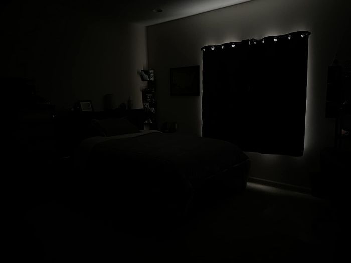 The same reviewer showing their room completely darkened, with the blackout curtains drawn for a peaceful, dark environment.