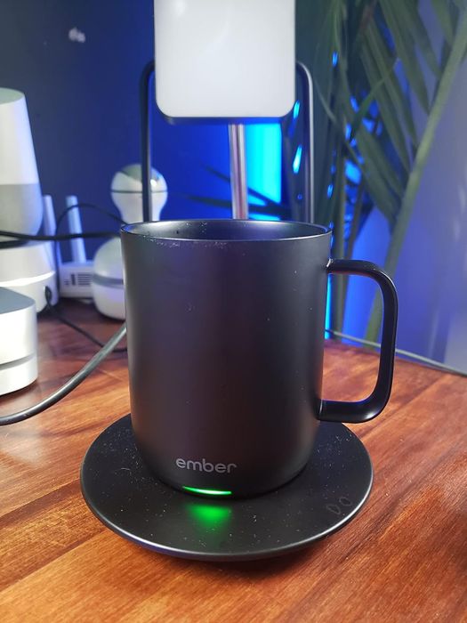 A reviewer displays the sleek black mug sitting on its charger.