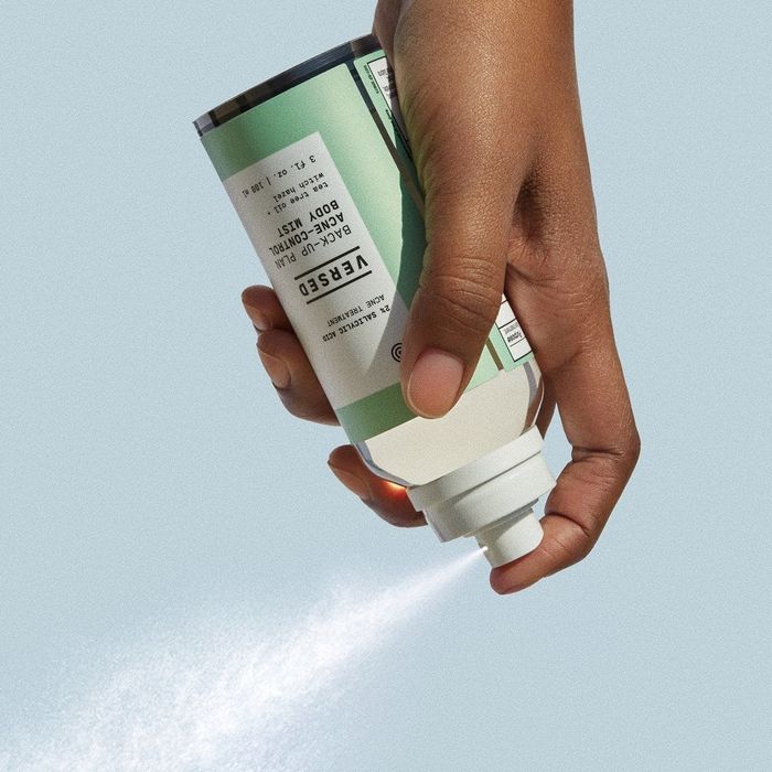 A model spraying the Versed Back-Up Plan Acne-Control Body Mist bottle.