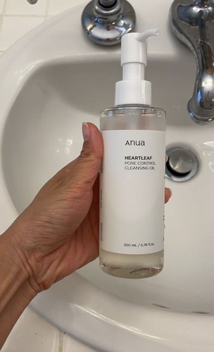 A hand holding a bottle over a sink.