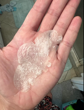 A hand holds a clear, translucent nose mask.