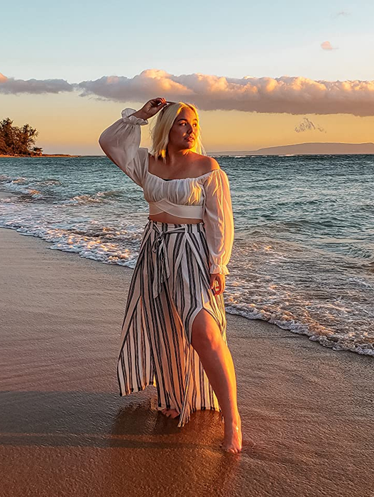side view of a reviewer wearing black and white striped pants on the beach