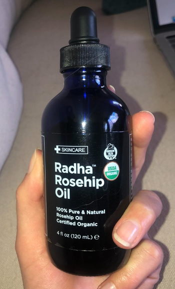 A reviewer can be seen holding a bottle of the oil.