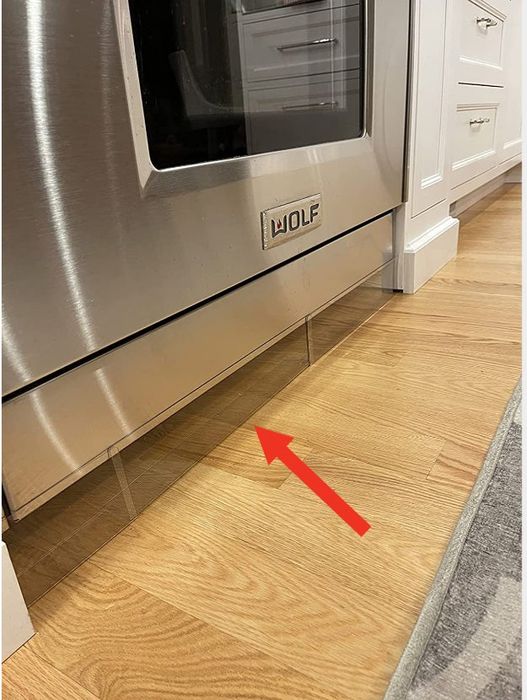 clear plastic blockers installed under a stove to stop toys from rolling underneath