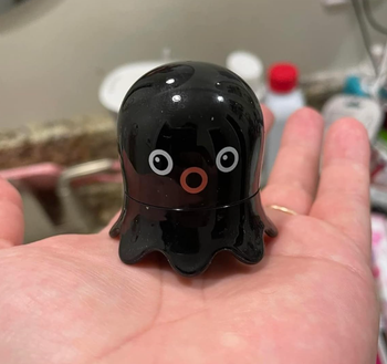 a reviewer holding the tiny octopus-shaped tool
