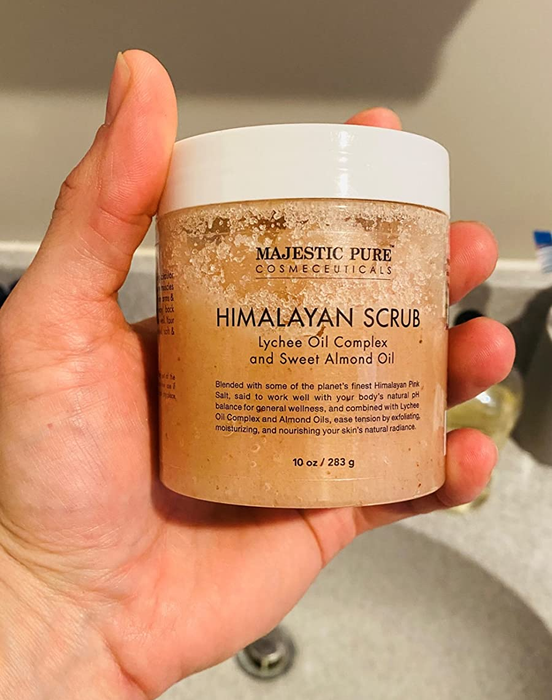 a reviewer showcasing the body scrub jar