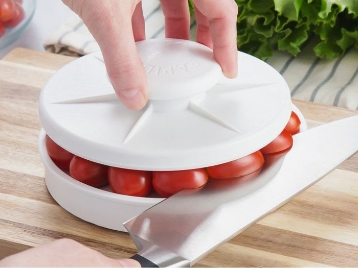 The same slicer in action, now slicing through several cherry tomatoes at once with precision and ease.
