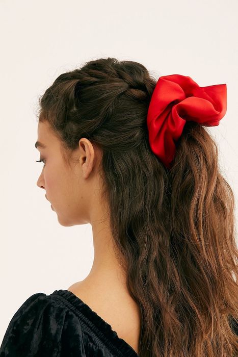 A model wearing a bright red scrunchie in a half-updo hairstyle.