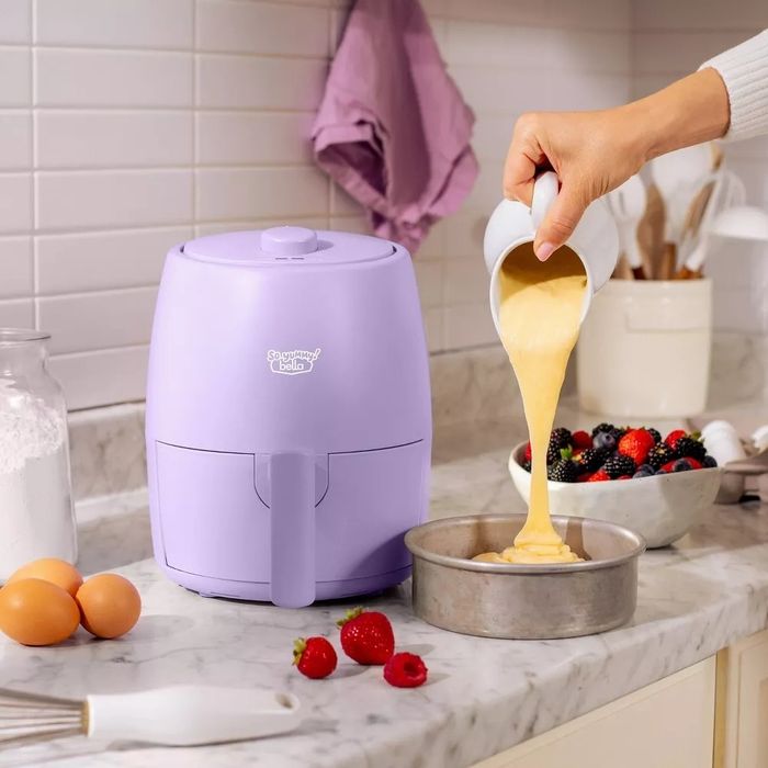 A person pours batter into the air fryer tray, ready to create a perfectly crispy snack.