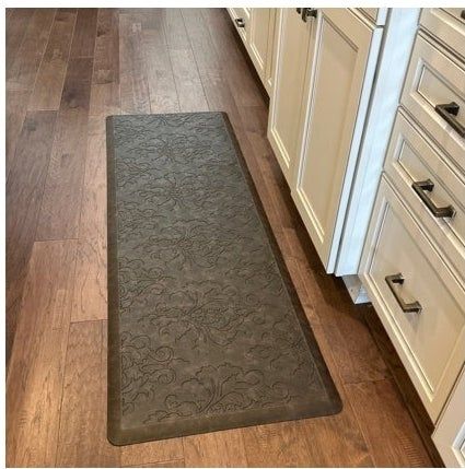 A kitchen featuring a wooden floor, cream-colored cabinets, and a detailed anti-fatigue mat. The article highlights tips for home decor and kitchen shopping essentials.