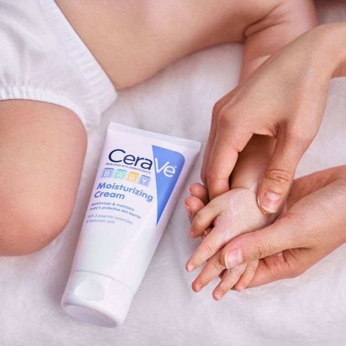 A baby’s hand being gently rubbed with lotion.