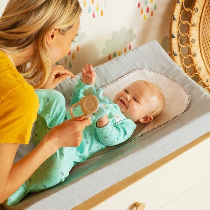 A woman plays with her baby on a changing mat