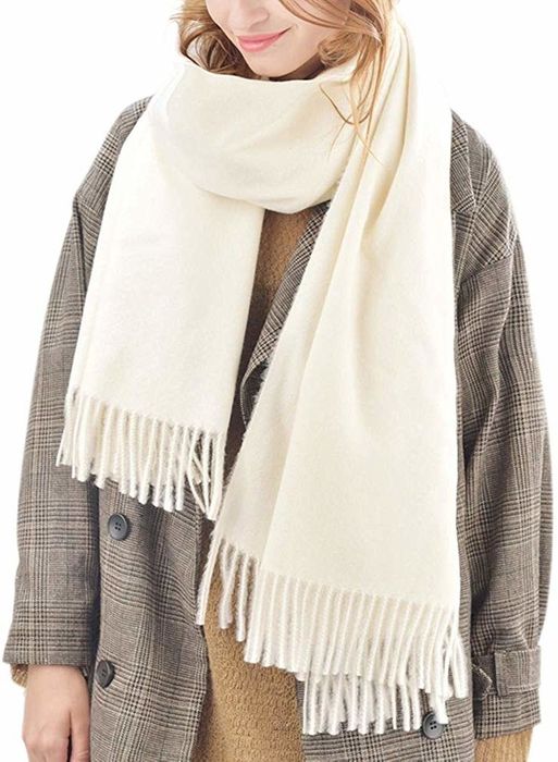 A model wearing the cream-colored scarf with fringe details