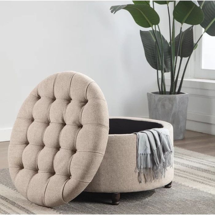 A light brown ottoman with its top removed, revealing the spacious storage compartment inside.