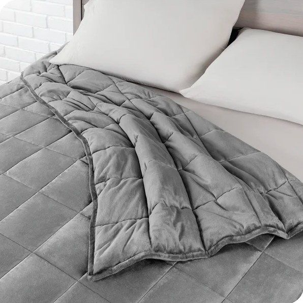 A gray cotton blanket spread over a bed.