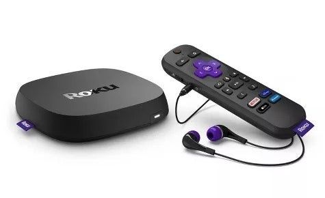 A Roku streaming device placed next to its remote and earphones designed for private listening.