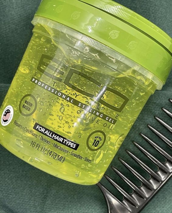 A jar of hair gel with a comb