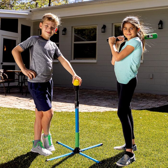 Two children standing outdoors, ready to play with a tee ball set