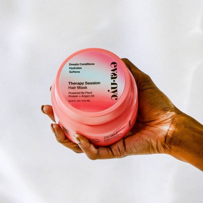 a model holding a tub of the hair mask