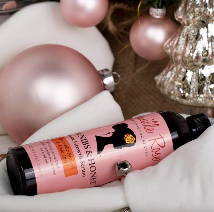 A bottle of hair serum featuring pink, white, and silver ornaments