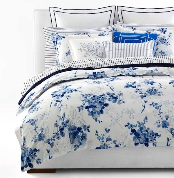 Bed arranged with blue and white floral and striped bedding