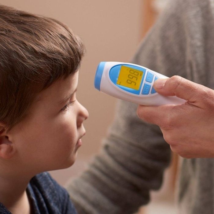 A child is having their temperature taken using a touchless thermometer.