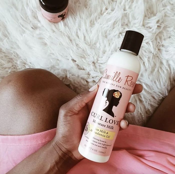 A person holding a bottle of hair milk