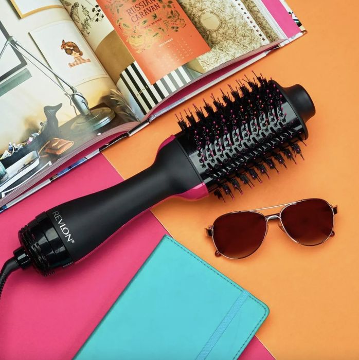 A pink and black hair dryer and styler, a pair of sunglasses, and a magazine
