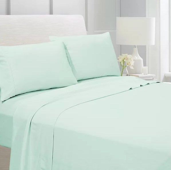 A mint-colored sheet set spread out on a bed.