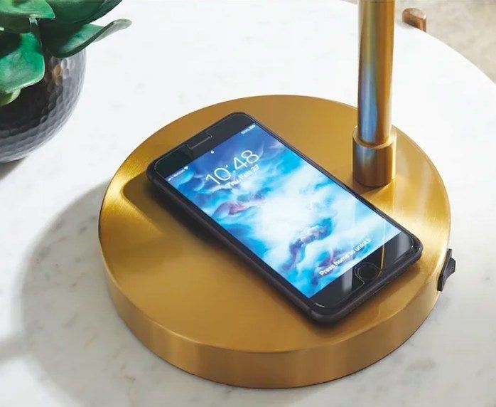 Phone placed neatly on the lamp base, showcasing the integrated charging feature.
