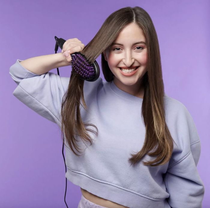 A person using a heated straightening brush