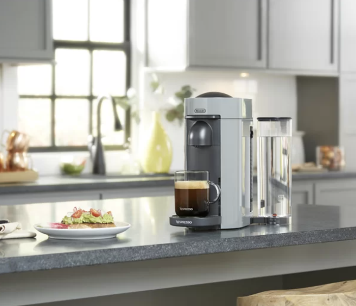Espresso maker sitting on a counter, accompanied by a glass mug filled with freshly brewed coffee.