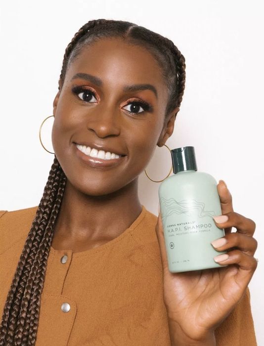 An image of Issa Rae holding a bottle of shampoo
