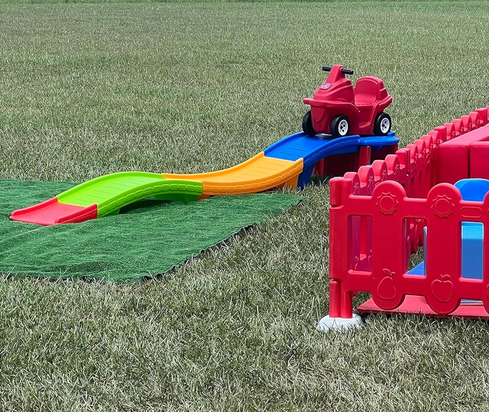 Children’s outdoor playset featuring a slide and climbing area set on grass
