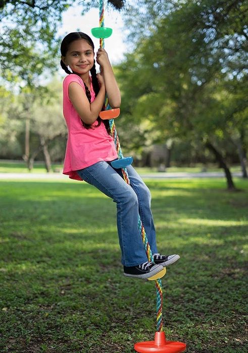 A child standing on the second rung of a colorful rope ladder